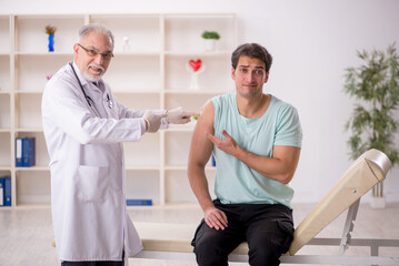 Obraz premium Young male patient visiting old male doctor in vaccination conce