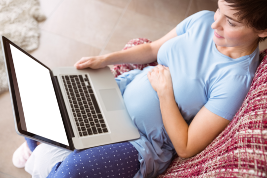 Pregnant woman using laptop at home