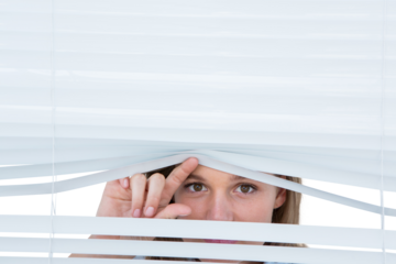 Woman peering through roller blind