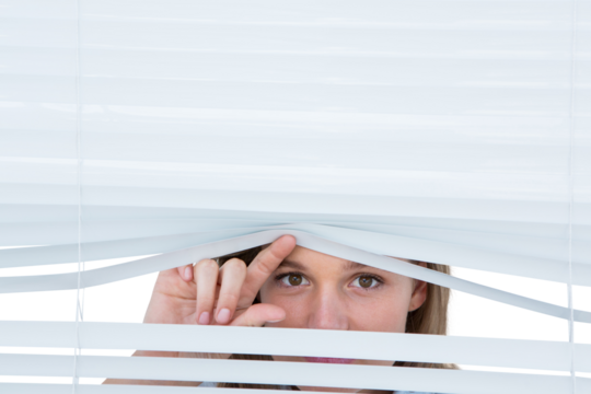 Woman peering through roller blind