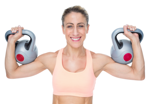 Happy female crossfitter lifting kettlebells looking at camera - Powered by Adobe