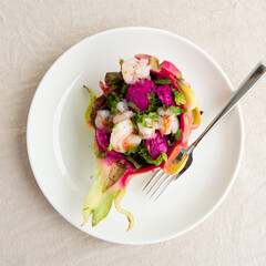 plate with salad with shrimp and pitahaya on a light table