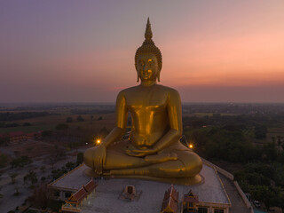 Obraz premium aerial view The moon was above the head of the biggest golden Buddha in the world..scenery red sky in twilight background. .golden big buddha is a popular landmark at wat Muang Ang Thong Thailand.