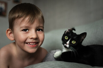 Fototapeta premium portrait of a little boy and a black domestic cat on a gray background
