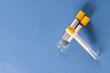 Three sample tubes of clear fluid with yellow lids, on blue background with copy space