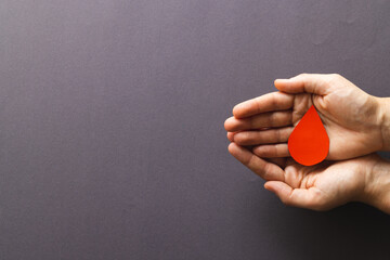 Hands of caucasian woman cupping blood drop, on grey background with copy space