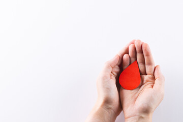 Hands of caucasian woman cupping blood drop, on white background with copy space