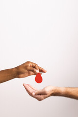 Hands of biracial man giving blood drop to caucasian man, on white background with copy space