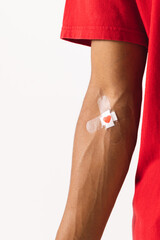 Midsection of biracial man with heart sticking plaster on arm, on white background with copy space