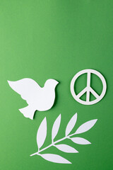 Obraz premium Close up of white dove and peace sign with leaves and copy space on green background