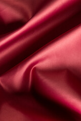 Fototapeta na wymiar Close up of plain red satin fabric with folds, copy space