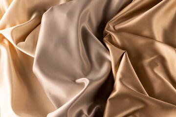 Close up of plain beige satin fabric with folds, copy space