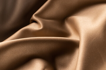 Fototapeta na wymiar Close up of plain beige satin fabric with folds, copy space