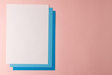 Fototapeta na wymiar Close up of white and blue paper on pink background with copy space