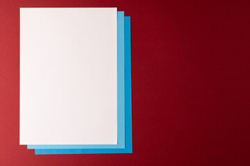 Close up of white and blue paper on red background with copy space