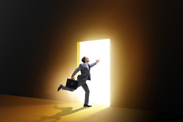 Businessman entering backlit door in escape concept