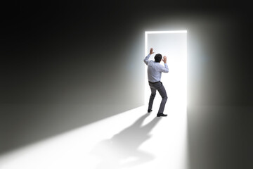 Businessman entering backlit door in escape concept