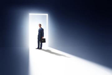 Fototapeta premium Businessman entering backlit door in escape concept