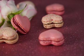 Heart-shaped macarons with roses on glittery pink background, Valentines day