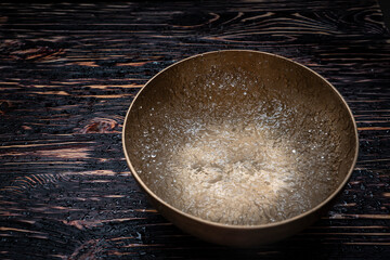 Drops of water fly into the air from hitting a Tibetan (singing) bowl. Cold boil. Tibetan bowl on a black background.