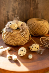 Quail eggs, quail feathers on a skein of thread on a dark wood background