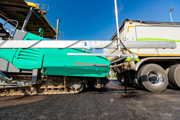 Obraz premium Level sensors for good road evenness placed on asphalt spreading machine, in the background truck is being prepared to loading into it