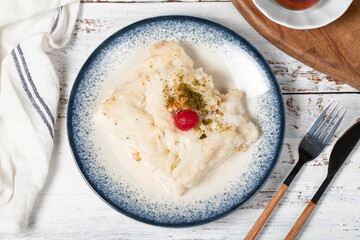 Güllaç dessert on wood background. Traditional Ramadan dessert. Güllaç dessert topped with sour cherry and pistachio. Top view