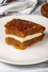 Bread pudding on wood floor. Traditional Ramadan dessert. Bread kadayif with cream in the middle. Local name kaymaklı ekmek kadayifi. Close up