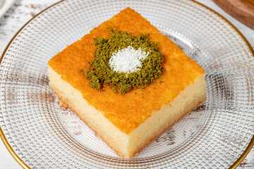 Revani dessert on wood background. Traditional Ramadan dessert. Revani dessert with pistachio and coconut. Close up