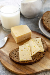Healthy food concept, breakfast, superfood. Fresh whole grain bread with cheese and a glass of almond milk on stone table. 