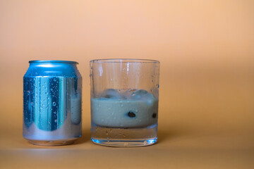 Glass of fresh cold chocolate drink sitting next to its can over blurry background