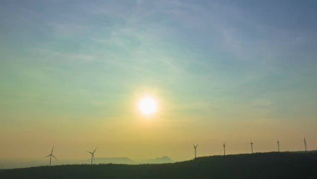 aerial hyperlapse view beautiful sunrise above wind turbines..scenery sky in the morning above the large dam..wind turbine on the top of mountain.Wind power generates electricity. Clean energy