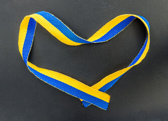 help Ukraine , blue and yellow Ukraine tape in a shape of heart on black background