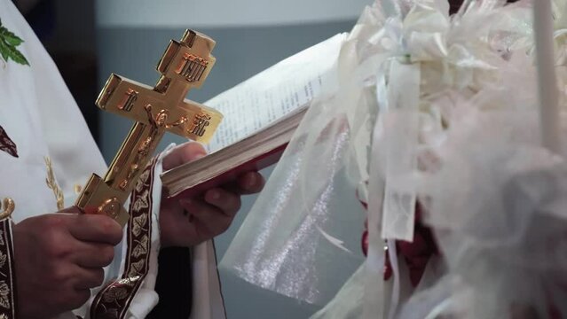 Religious marriage in the Orthodox church. Priest holding cross and reading from the Bible during wedding matrimony.