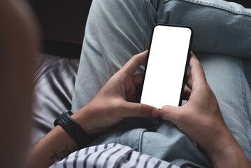 Mockup, blank screen cell phone. Men hand holding, using mobile phone on sofa at home office. copy space for advertise text. contact business, people communication. technology device concept