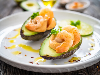 Avocado with fried prawns on and cocktail sauce on wooden background
