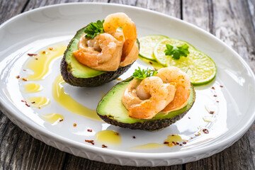 Avocado with fried prawns on and cocktail sauce on wooden background
