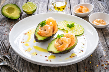 Avocado with fried prawns on and cocktail sauce on wooden background
