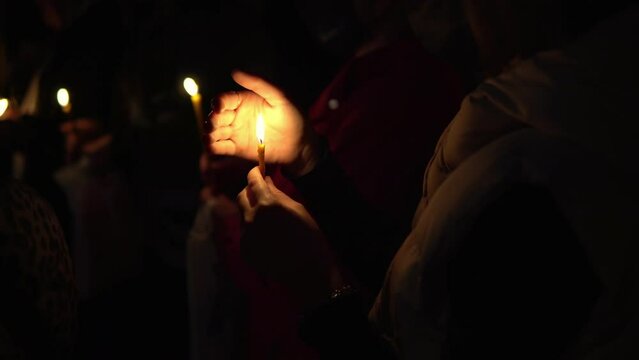 Woman holding lighted candle in her hands at night, Orthodox Easter rithual at midnight - symbol of the Christian faith