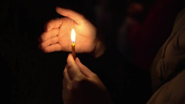 Woman holding lighted burning candle in her hands on Easter at midnight, as Ortodox sign and symbol of Christian faith