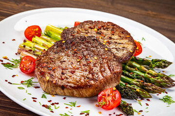 Barbecued beef steak with green asparagus on wooden table

