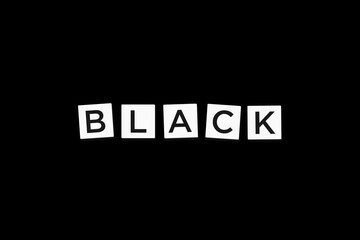 The word BLACK, spelt with letter Scrabble tiles on a black background