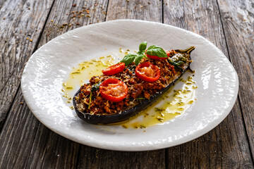 Roasted aubergine stuffed with minced meat and cheese on wooden table
