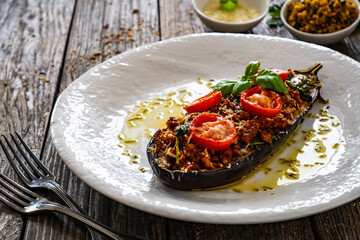 Roasted aubergine stuffed with minced meat and cheese on wooden table
