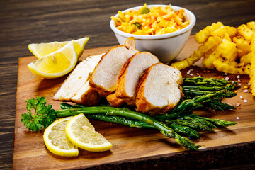 Sliced tasty roast chicken breast, green asparagus and cabbage on wooden table 