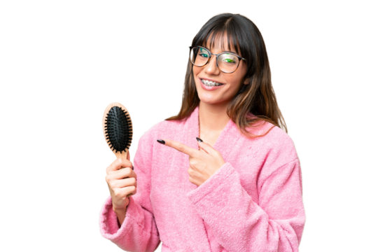Young woman with hair comb over isolated chroma key background and pointing it