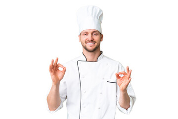 Young caucasian chef over isolated chroma key background showing an ok sign with fingers