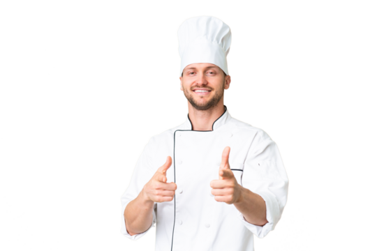 Young caucasian chef over isolated chroma key background pointing to the front and smiling