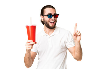 Young handsome man holding soda while watching a 3D movie over isolated chroma key background intending to realizes the solution while lifting a finger up