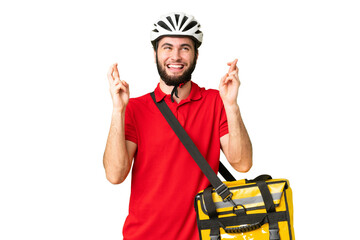 Young delivery man with thermal backpack over isolated chroma key background with fingers crossing